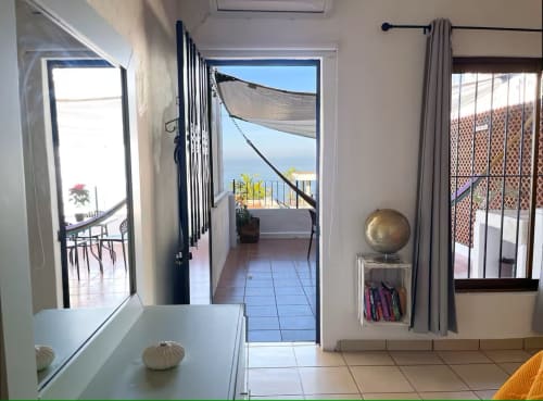 Bright Puerto Vallarta apartment with sea view terrace, open glass doors leading to balcony with ocean vista, tiled flooring,