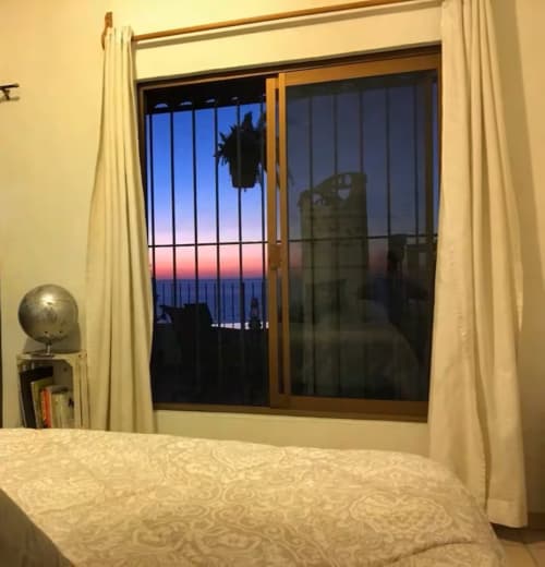 Bedroom with ocean view balcony at sunset, Anita Ocean View, Puerto Vallarta apartment with cream bedding and curtains