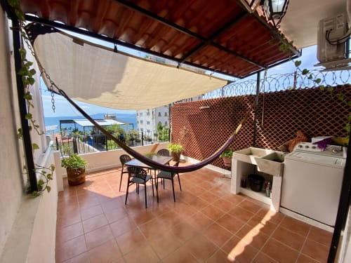 Sunny rooftop terrace at Anita Ocean View Puerto Vallarta with sea views, hammock, dining area, and washer-dryer