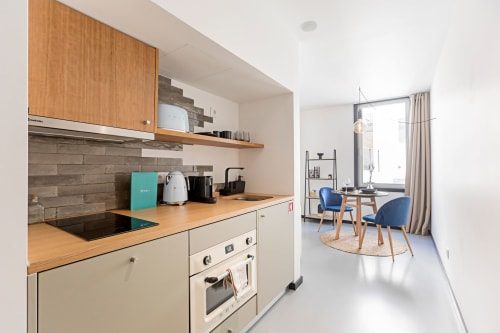 Kitchenette moderna com armários em madeira e zona de refeições, hotel Benefit Collection no Porto