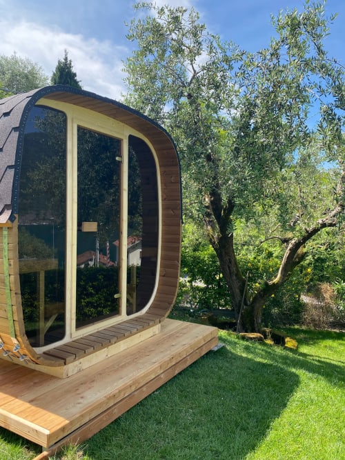 Modern pod cabin at Verdolivo B&B in Sale Marasino with curved wood design, glass doors, wooden deck, surrounded by olive