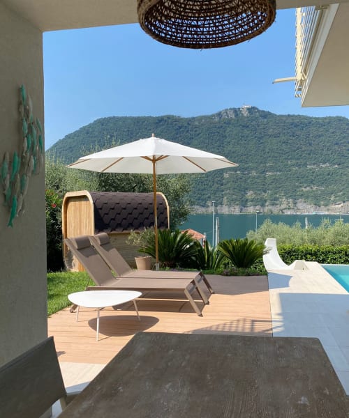 Verdolivo lakeside terrace with lounge chair, umbrella, and mountain views in Sale Marasino