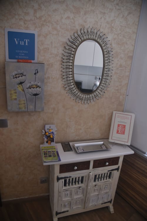 Entrada decorativa en alojamiento vacacional de Benavente con espejo ornamentado, señalización VuT y mueble de madera