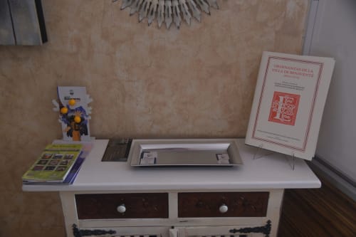 Display shelf in Benavente tourist apartment with books, decorative items, and metal sunburst wall art above