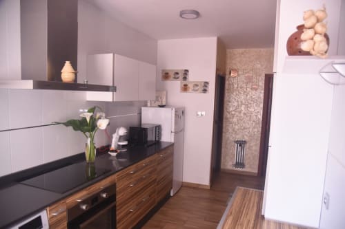 Modern kitchen with white cabinets, wooden drawers, black countertop and stainless steel appliances in Benavente city center