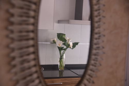 White calla lilies in glass vase on desk at Benavente tourist apartment, white tiled wall background