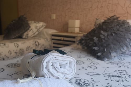 Rolled white towel with black bow on patterned bedding at Benavente city center rental apartment