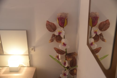 Arte floral prensado con tulipanes burdeos y orquídeas blancas en habitación del hotel Benavente