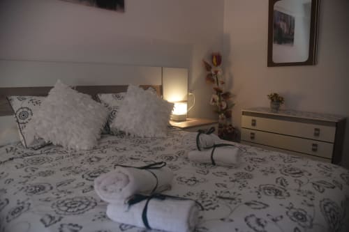 Modern bedroom in Benavente city center apartment with decorative pillows, bedside lamp, and floral wall decor