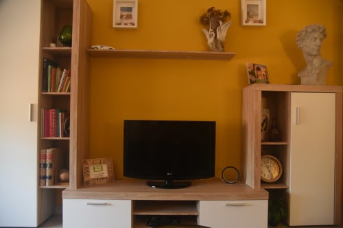 Moderno salón con paredes naranjas, mueble TV en madera y estantería en apartamento turístico de Benavente