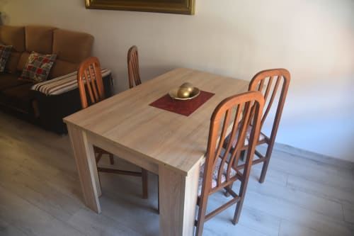 Light wood dining table with orange chairs in Benavente apartment living room near brown sofa