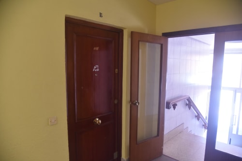 Hallway with yellow walls, dark wooden doors, and glass partition in Benavente tourist apartment