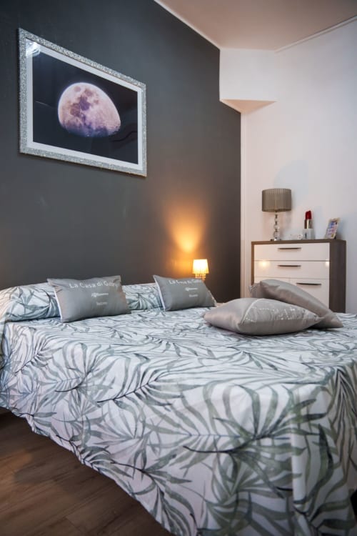 Modern bedroom at Navigli Affittacamere in Rozzano with moon artwork, patterned bedding, and ambient lighting