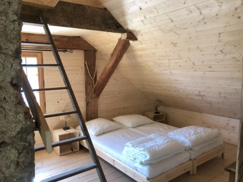 Cozy alpine bedroom at Les Chalets de l'Eau Rousse with wooden beam ceiling, loft ladder, and white bedding in Celliers, La