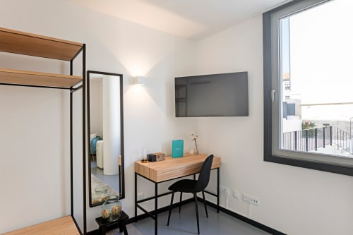 Estudio moderno en Oporto con escritorio de madera, televisor y vistas a la ciudad desde la ventana del hotel Benefit Collection
