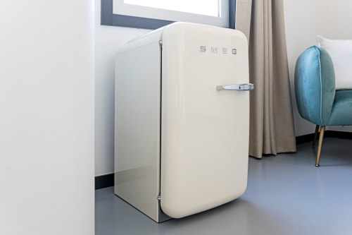 Refrigerador SMEG color crema en estudio de hotel moderno en Oporto con zona de estar y vista a la ventana