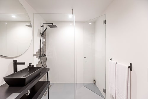 Baño moderno en hotel de Porto con lavabo negro tipo vasija, ducha lluvia, mamparas de vidrio y espejo redondo