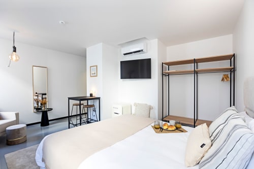 Modern studio bedroom at Benefit Collection Porto with bed, kitchenette, workspace, TV, and wardrobe in minimalist design