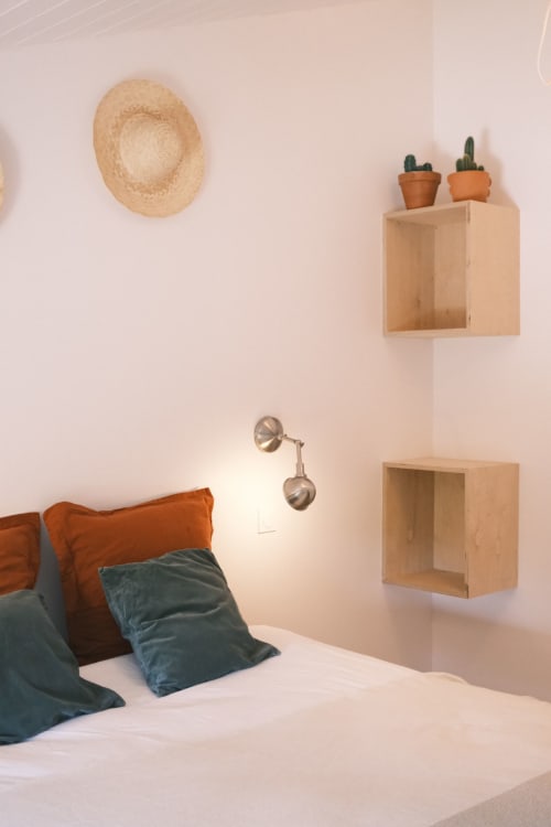 Chambre cosy de la Maison Monsieur Léger avec étagères en bois, cactus, chapeau de paille et coussins colorés