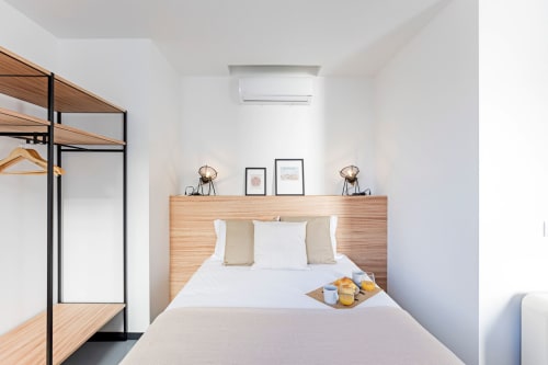 Chambre d'hôtel moderne et lumineuse à Porto avec lit en bois, tête de lit murale, climatisation et décoration minimaliste