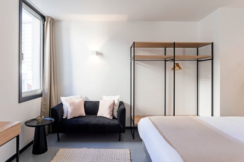 Chambre de studio moderne à l'hôtel de Porto avec lit à baldaquin noir, canapé sombre et grande fenêtre avec vue sur la ville
