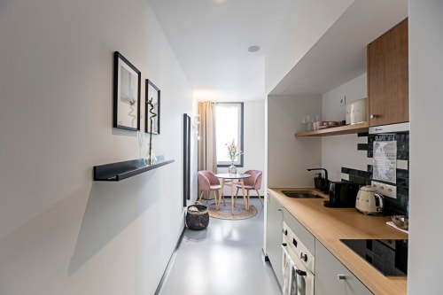 Cuisine couloir moderne de studio hôtelier à Porto avec comptoirs en bois, armoires blanches et vue sur la salle à manger