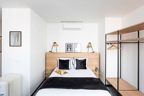 Modern studio bedroom at Benefit Collection Porto hotel with wood headboard, black accents, and wall-mounted shelving