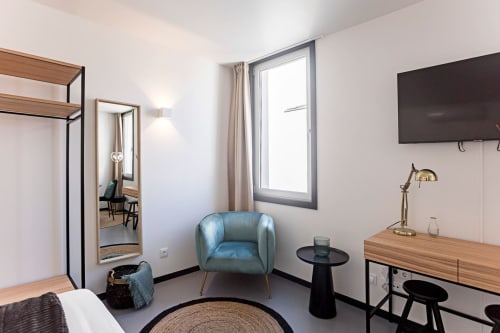 Estudio moderno en Oporto con sillón azul, escritorio de madera, cocineta y vistas a la ciudad