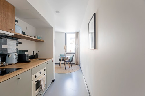 Cocina americana moderna con zona de comedor en estudio de hotel en Oporto, muebles de madera y decoración contemporánea