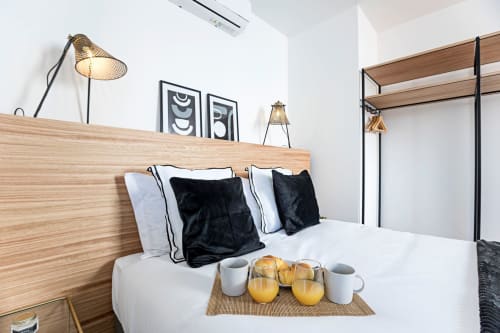 Habitación moderna en Benefit Collection Porto con cama de madera, almohadas negras, sábanas blancas y desayuno de bienvenida