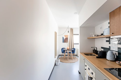 Modern studio apartment kitchen and dining area at Benefit Collection Porto hotel with wooden countertops, blue chairs, and