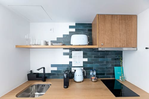 Modern kitchenette in Porto hotel with wooden countertop, dark teal subway tile backsplash, stainless steel sink, and white