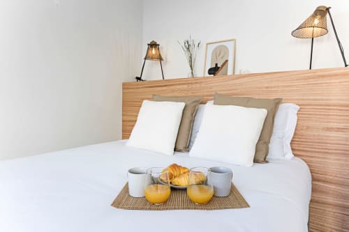 Bright bedroom in Porto's Benefit Collection hotel with wooden headboard, white pillows, breakfast tray with juice and