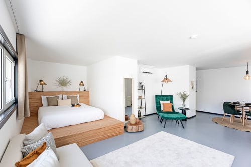 Estudio superior en Benefit Collection Porto con cama de plataforma de madera, sillón verde azulado y zona de comedor