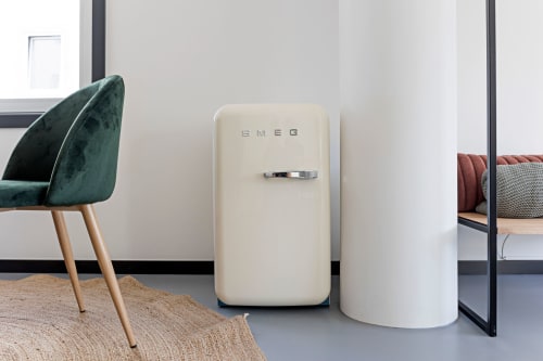 Refrigerador SMEG color crema moderno en apartamento Superior Studio del hotel Benefit Collection en Porto, con sillón de terciopelo verde y