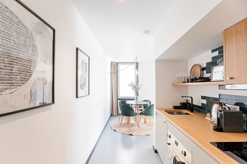 Cocineta Studio Superior moderna con encimeras de madera, gabinetes blancos, área de comedor y sala de estar en Benefit Collection