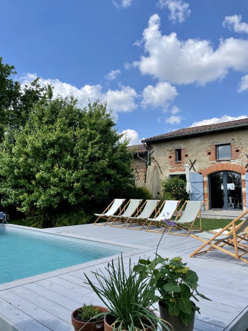 Terrasse piscine de villa de luxe avec chaises longues dominant une maison en pierre à Montaut, France