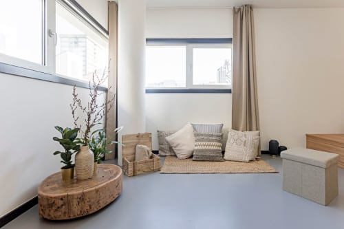 Moderno estudio superior en Benefit Collection Porto con zona de descanso, cojines, accesorios de madera y plantas en maceta