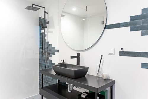 Baño moderno en Superior Studio de Benefit Collection Porto con lavamanos negro, espejo circular y azulejos de pizarra