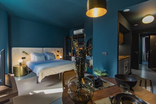 Modern one-bedroom apartment at Benefit Collection Porto with teal walls, kitchenette, dining area, and bedroom with blue