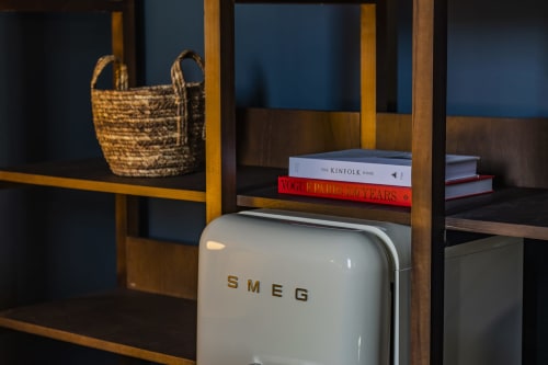 Retro SMEG refrigerator in Porto hotel apartment with decorative basket and books on wooden shelving