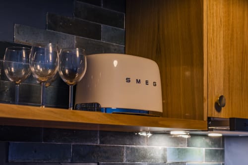 SMEG toaster and wine glasses on wooden shelf in Porto apartment kitchenette