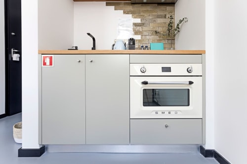 Cocina moderna en estudio compacto del hotel de Porto con horno SMEG, estufa, encimera de madera y muebles claros