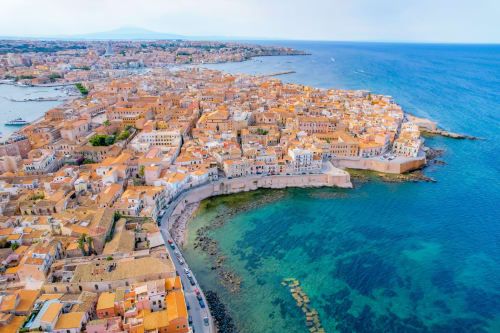 Vista aerea del suggestivo centro storico di Siracusa con tetti in cotto, acque turchesi del Mediterraneo e antichi edifici