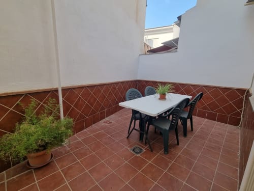 Cozy terrace at CTH Granada cottage in Armilla with white table, black chairs, potted plants, and red tile flooring