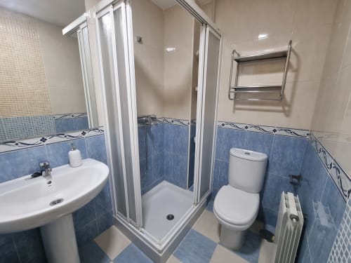 Modern bathroom at CTH Granada cottage in Armilla with blue and cream tiles, shower enclosure, toilet, sink and heated towel