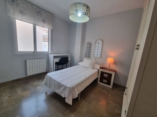 Modern bedroom in Boabdil House cottage at CTH Granada, Armilla, with bed, nightstand, desk, and mountain views from window