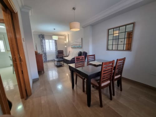 Boabdil House dining area at CTH Granada with black table, wooden chairs, living room, and mountain views