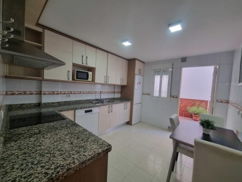 Modern kitchen with granite countertops, white cabinetry, and dining area in Boabdil House cottage at CTH Granada, Armilla