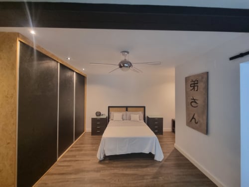 Dormitorio moderno en Penthouse CTH Granada Gracia con cama queen, armario de madera oscura, mesitas de noche, ventilador de techo y decoración mural asiática